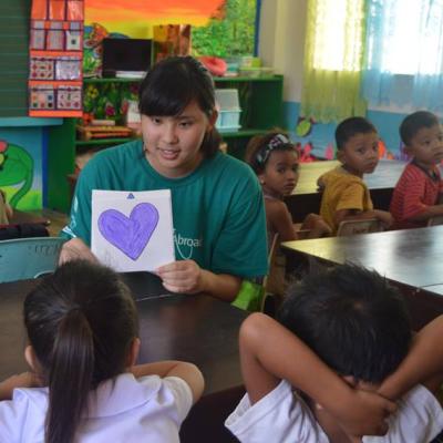 Een vrouwelijke Japanse vrijwilliger geeft les op een kinderopvang project terwijl ze vrijwilligerswerk doet in de Filippijnen. Een Japanse vrijwilliger werkt met kinderen en geeft les over vormen op het kinderopvang project in de Filippijnen.